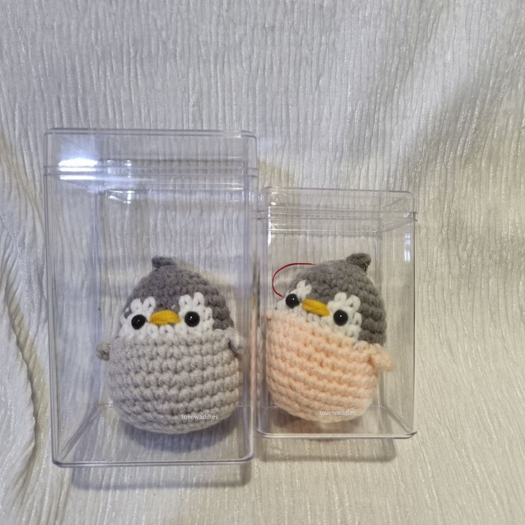 2 different sized acrylic boxes with one crochet penguin in each of the box